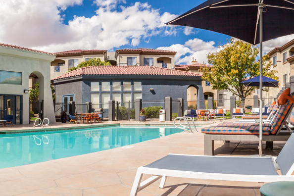 Outdoor pool and patio with lounge chairs and umbrella