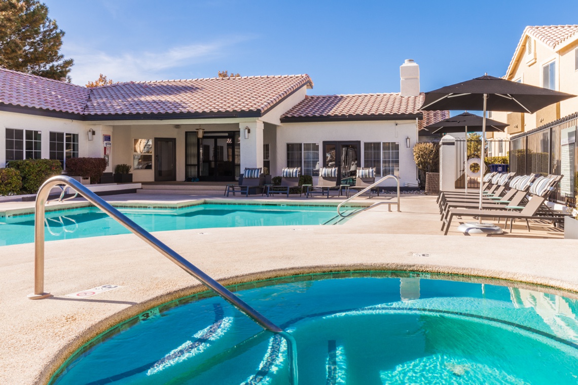 Outdoor pool and hot tub with apartment clubhouse in the background