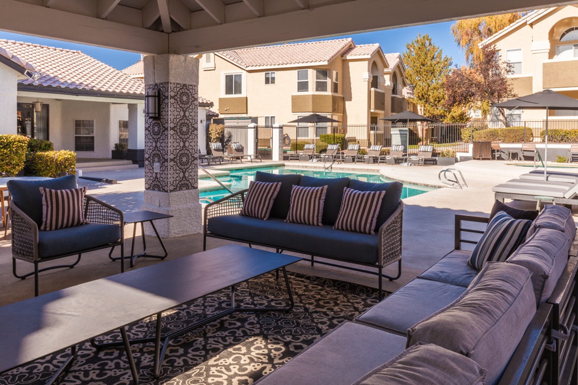 Covered patio with lounge chairs, next to an outdoor pool