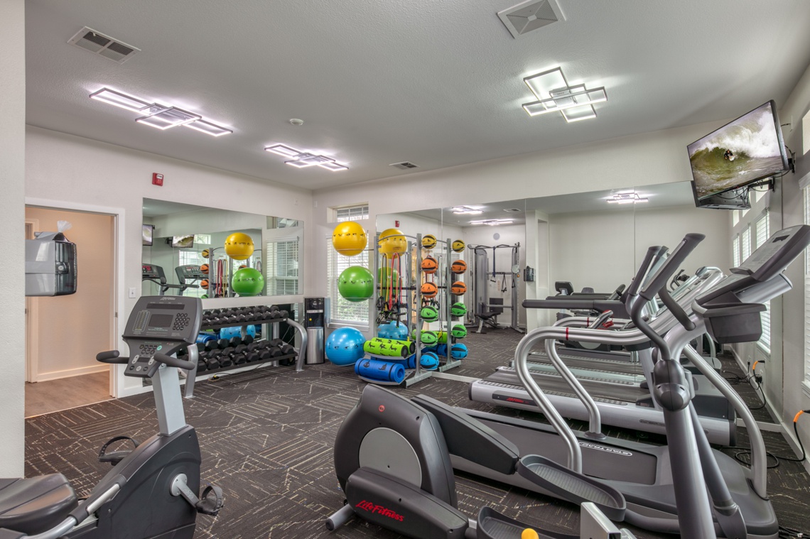 Gym with workout equipment, mats, and free weights