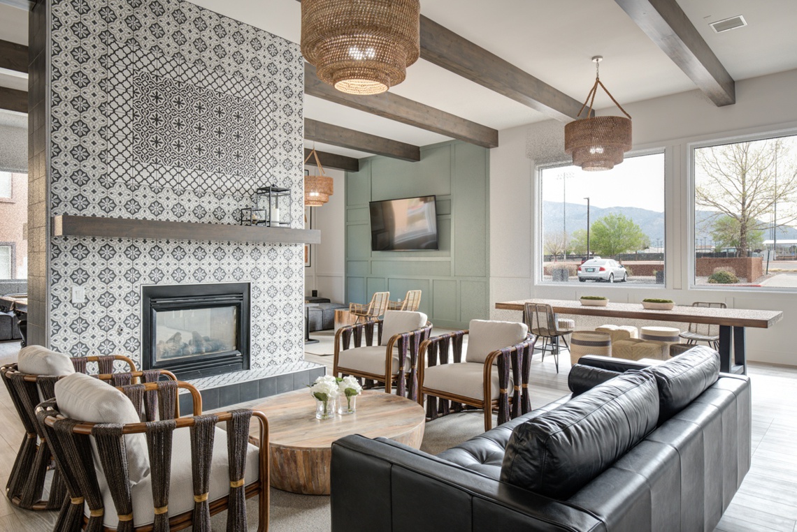 Clubhouse with large tiled fireplace, lounge chairs, couch, and pendant lamps