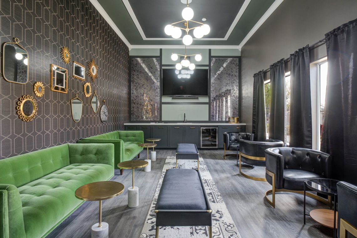 Member lounge with dark walls, moody lighting, and green velvet couch