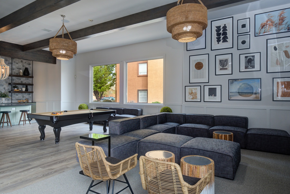 Clubhouse with couches and framed art, with pool table in the background