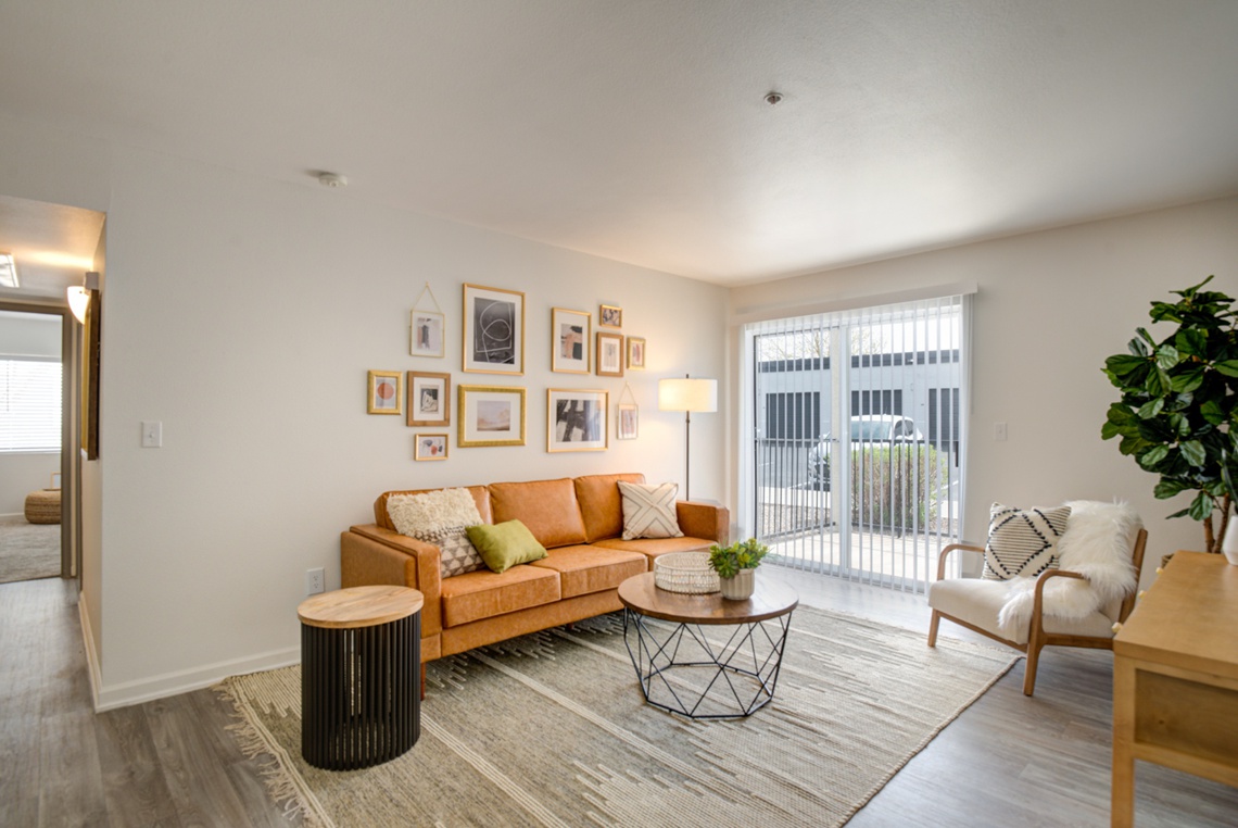 Living room with orange couch and small coffee table, with an outdoor patio in the background.