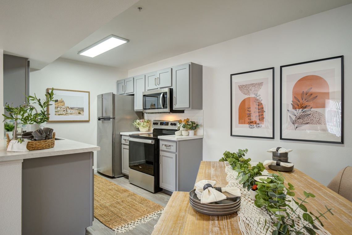 Apartment unit kitchen with framed art on the walls and stainless steel appliances
