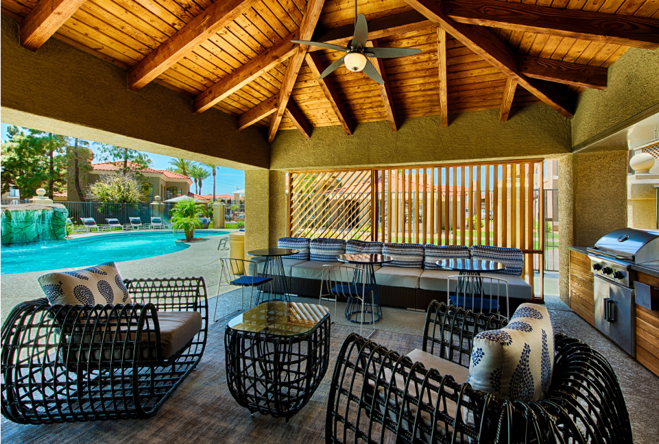Covered patio area near pool with seating and barbecue grill
